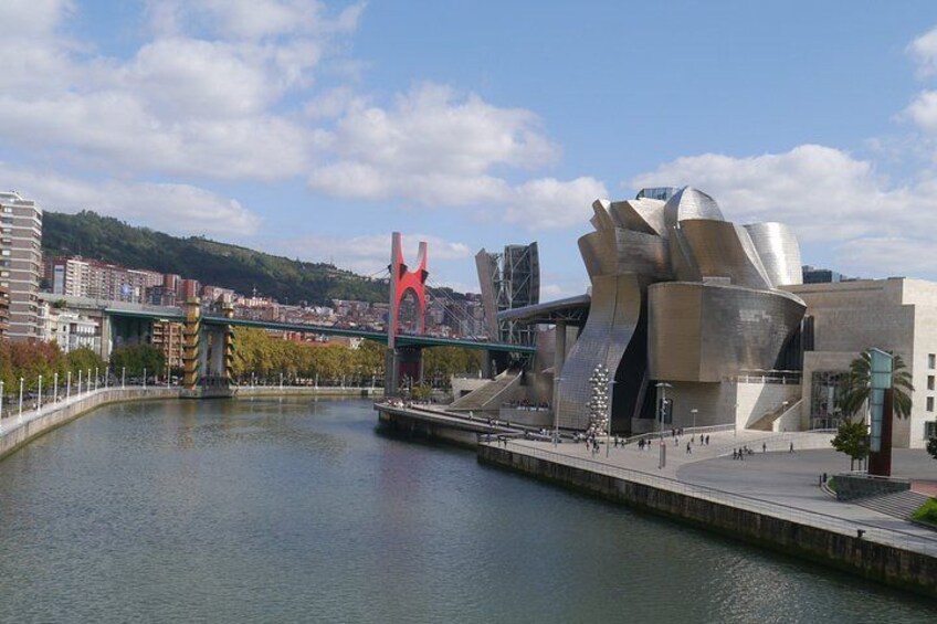 Un fiume, un edificio moderno dal design originale, un ponte rosso e uno skyline sullo sfondo. 3