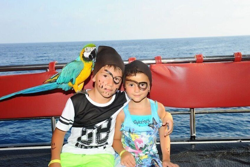A person with a parrot on their shoulder, sitting on a boat with a red railing and the ocean in the background. 5