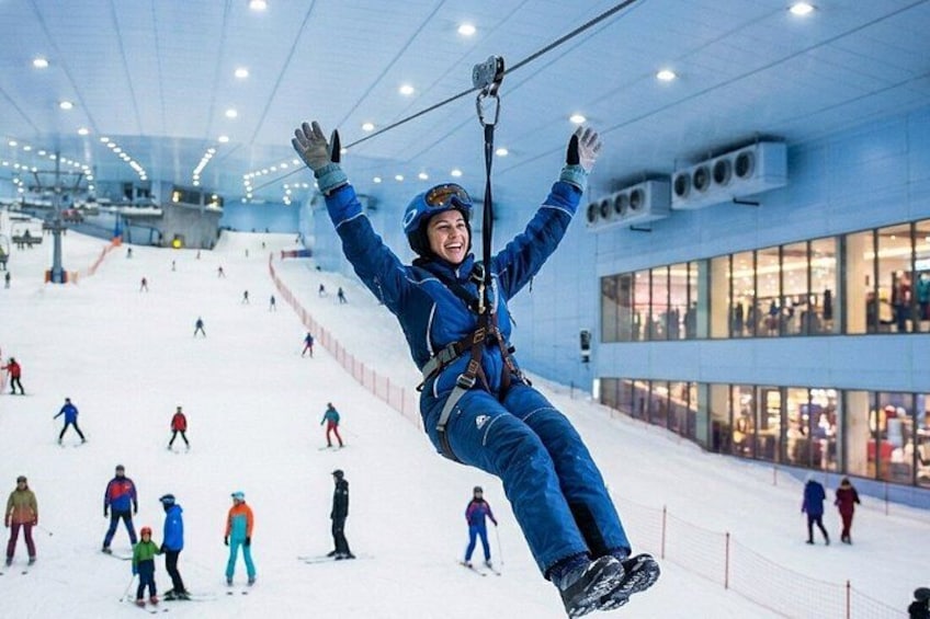 En person svæver i luften på en zipline i et indendørs skianlæg. 4