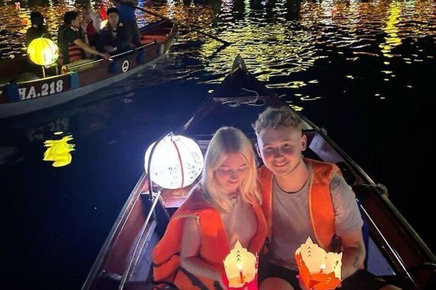 Una barca con persone che indossano giubbotti di salvataggio, una lanterna accesa e una superficie d'acqua calma di notte. 4