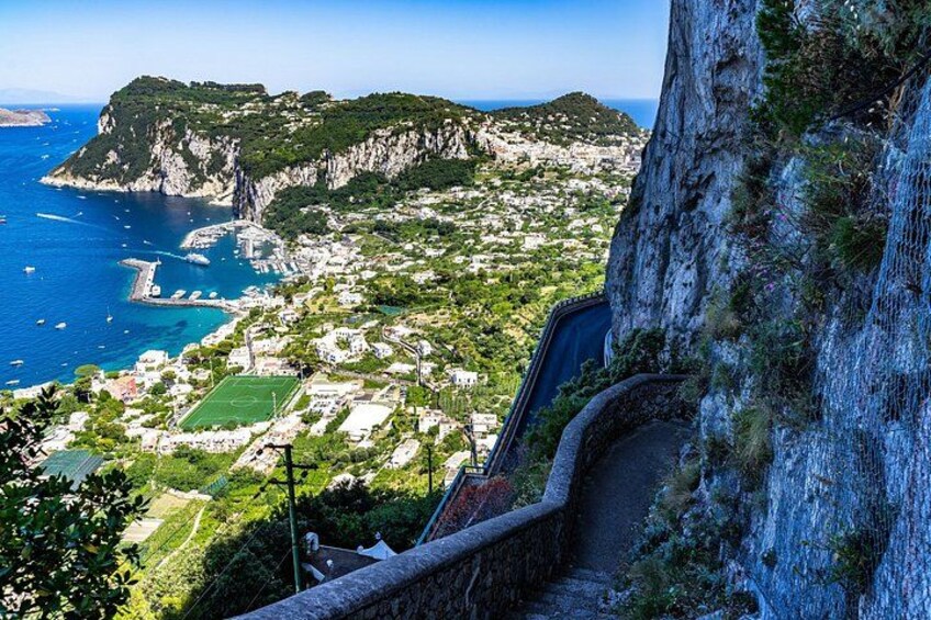 A coastal town with a steep cliff, a clear view of the sea, and a winding road. 3
