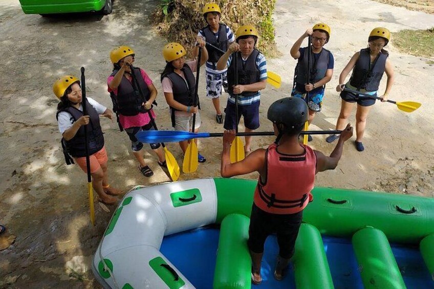 Eine Gruppe von Menschen mit Rettungswesten und Helmen bereitet sich auf eine Rafting-Tour vor. 5