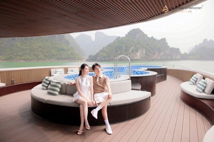 Una pareja sentada en una terraza curva con vistas a una costa montañosa. 4