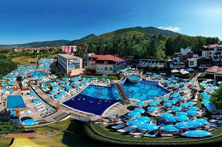 A resort with multiple swimming pools, lounge areas, and a mountainous backdrop. 1