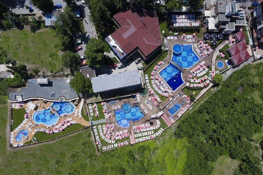 An aerial view of a resort with multiple swimming pools, sun loungers, and a large building. 2