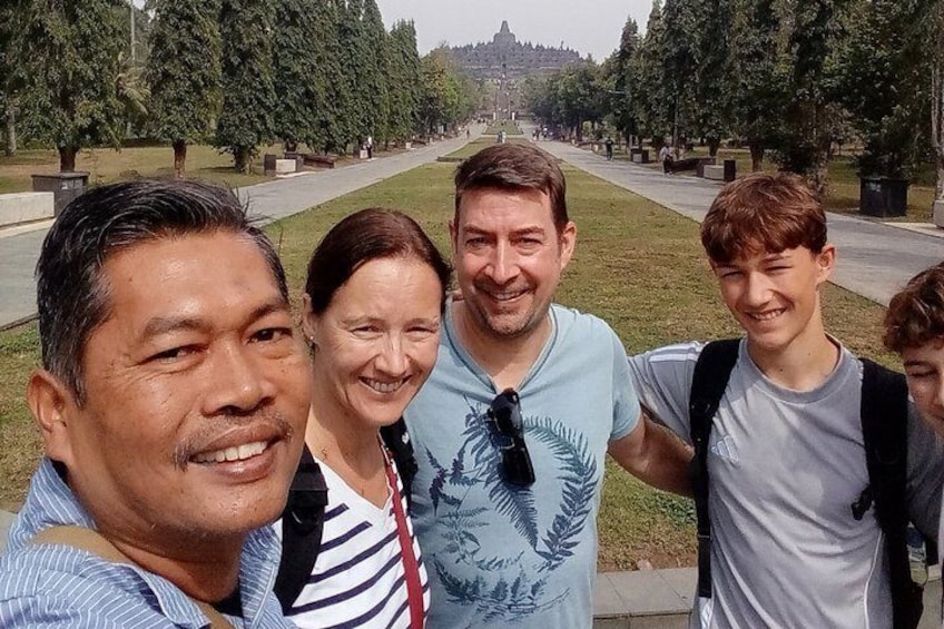 Un grupo de personas de pie en un parque con un camino largo y árboles al fondo. 1
