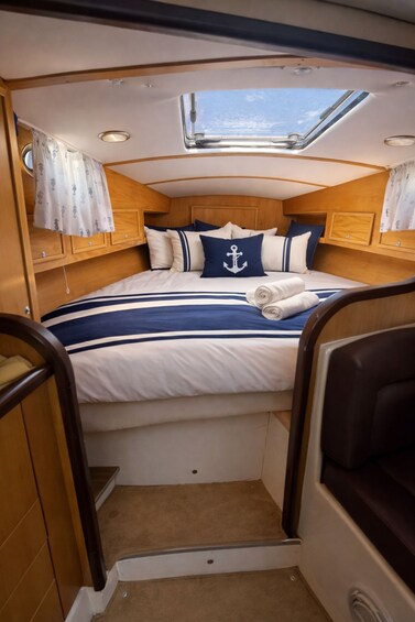 A compact, nautical-themed cabin with a bed, wooden walls, and a skylight. 5