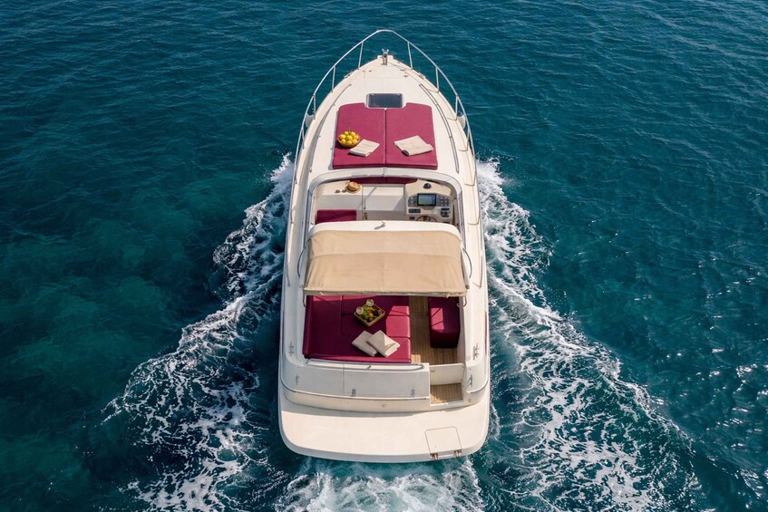 A white motorboat with a red deck, moving through clear blue water. 2