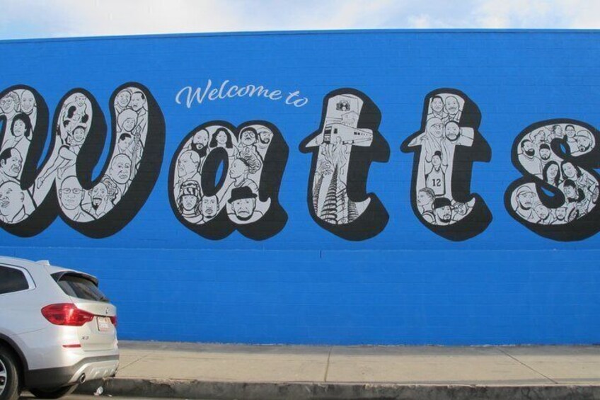 Pared azul con un gran mural 'Welcome to Watts' que muestra a varias personas. 4