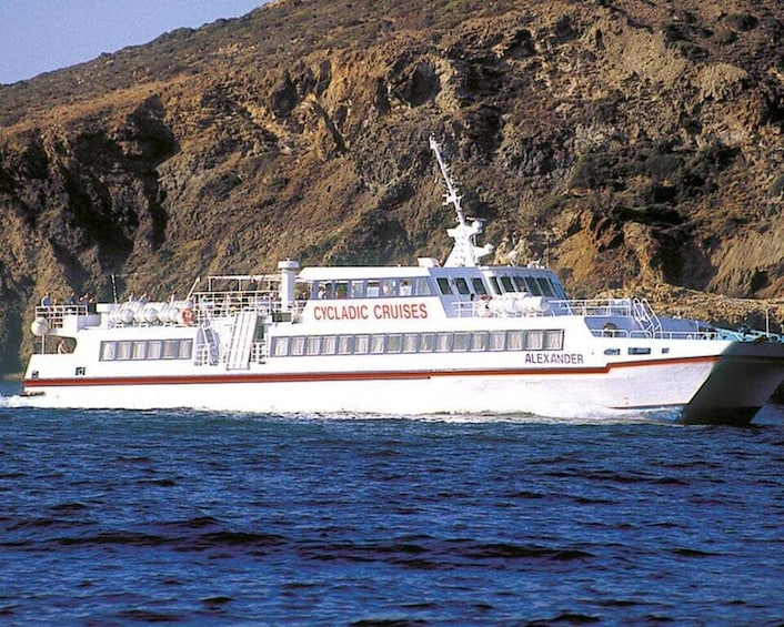A white cruise ship named 'Alexander' with 'CYCLIC CRUISES' written on its side, sailing on blue waters with a rocky coastline in the background. 3