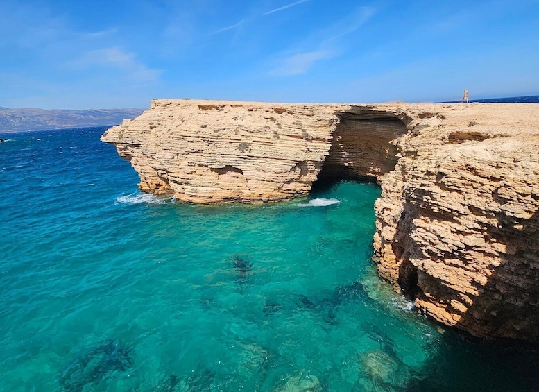 A coastal cliff with a clear blue sea and a person walking on the top. 2