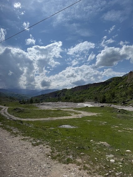 A mountainous landscape with a winding river, green fields, and a clear sky. 2