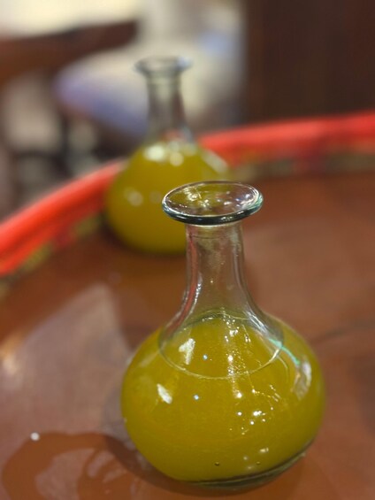 Una botella de vidrio llena de líquido amarillo sobre una mesa. 2