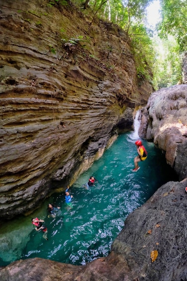 A group of people swimming in a natural water channel surrounded by rocky cliffs. 2