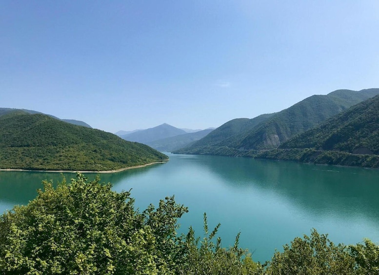 A calm lake surrounded by lush green hills under a clear sky. 5
