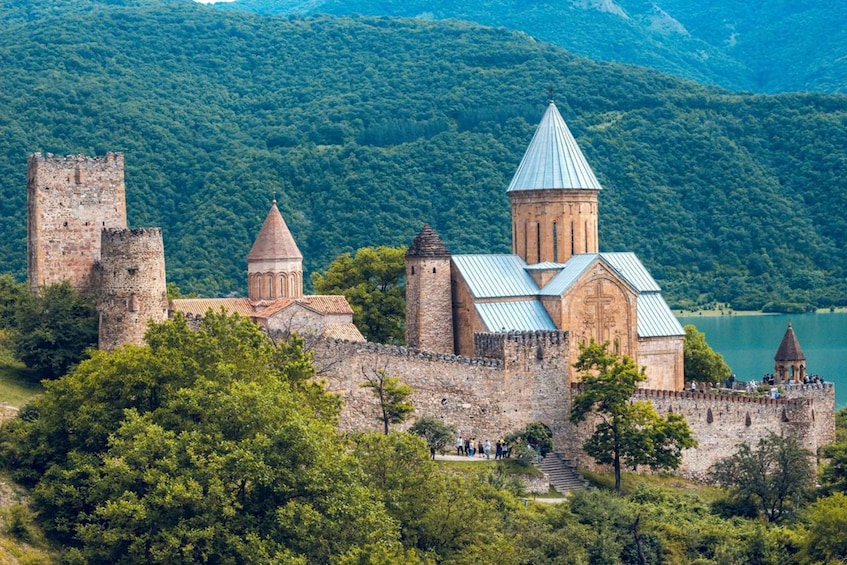 A historic castle with a church, surrounded by lush green hills and a lake. 2