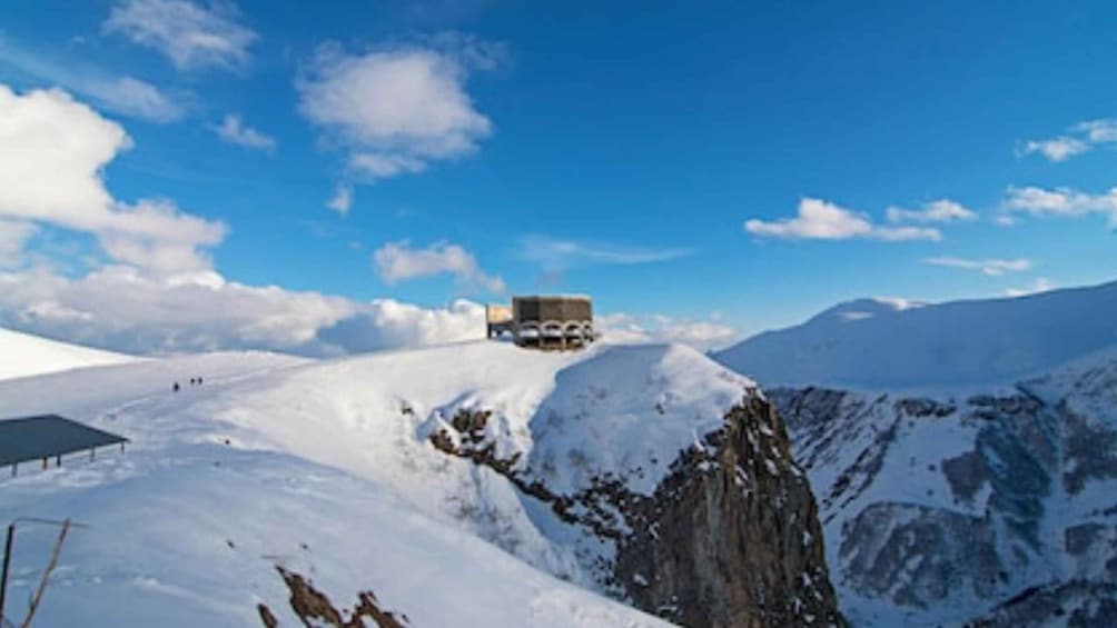 A snow-covered mountain with a building on top and a clear blue sky. 4