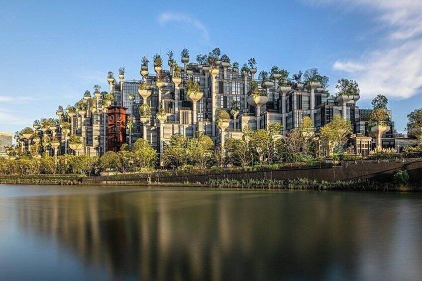 Un paisaje urbano moderno con un complejo de edificios grande, una masa de agua tranquila y un puente. 3