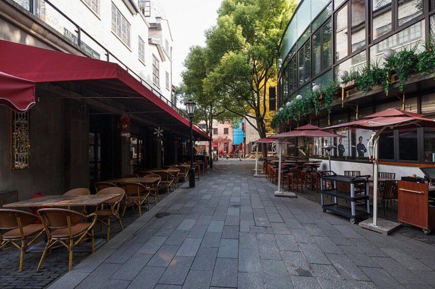 A street with outdoor seating, tables, and umbrellas. 2