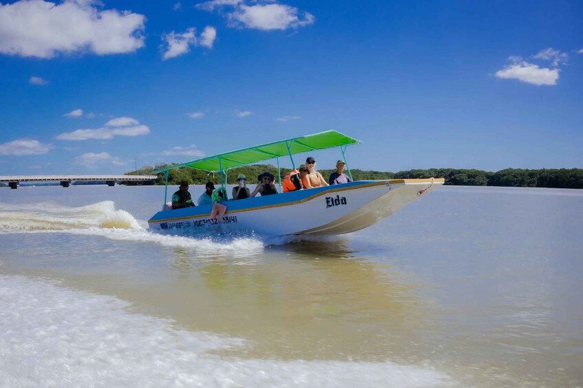 A boat with passengers, a bridge in the background, and a clear sky. 1