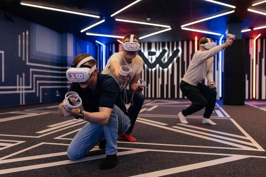 People playing a VR game in a modern indoor space with geometric patterns on the walls and floor. 2