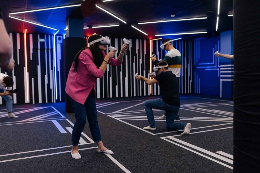 People using VR headsets in a modern, geometrically designed room with a black and white striped wall. 5