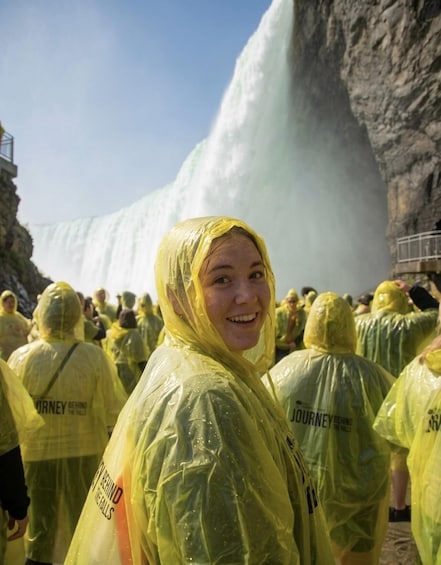 A group of people in yellow rain ponchos standing in front of a large waterfall. 4