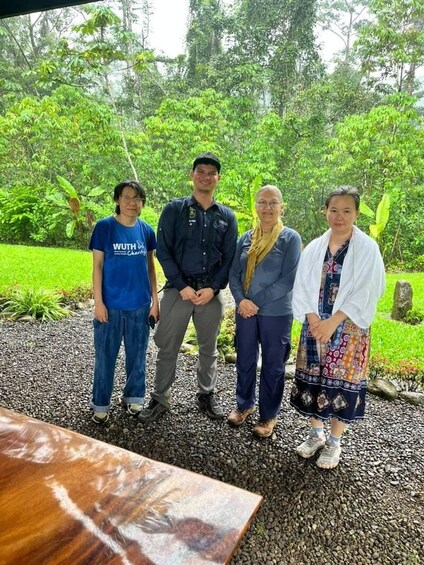 Four people standing on a gravel path surrounded by greenery. 4