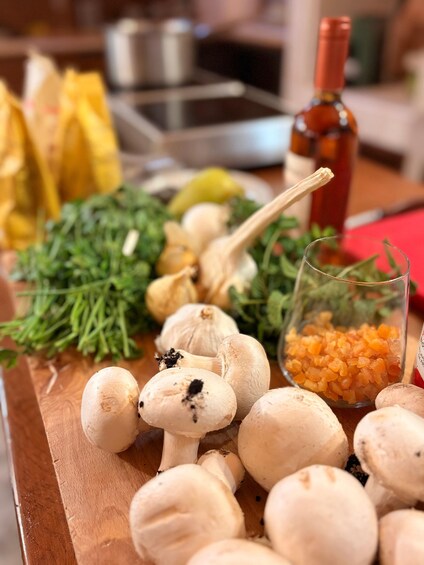 Een houten snijplank met champignons, knoflook, peterselie en een glas sinaasappel-wortelsap. 2
