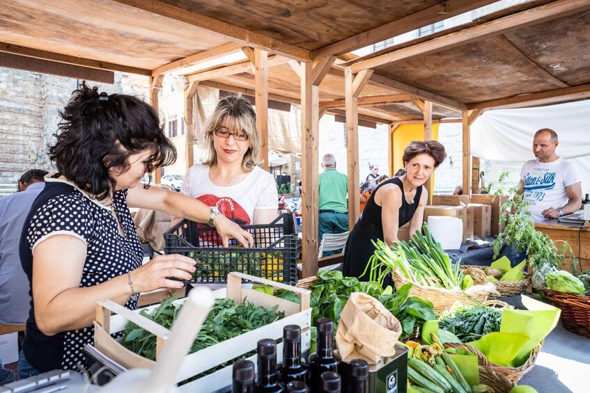 Een markt in de open lucht met houten kraampjes, verse producten en mensen die winkelen. 1