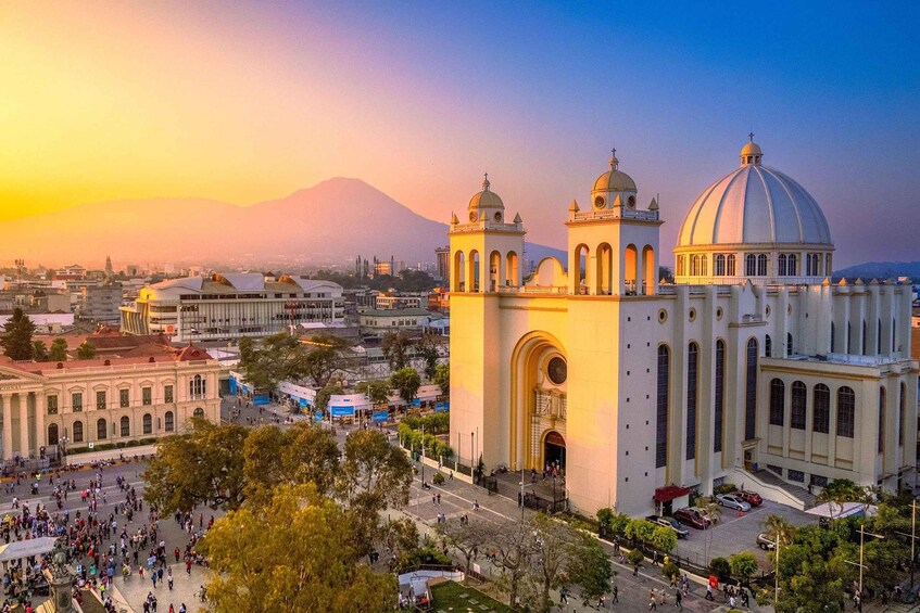 A large cathedral with two towers and a dome, surrounded by a busy square with people and trees. 4
