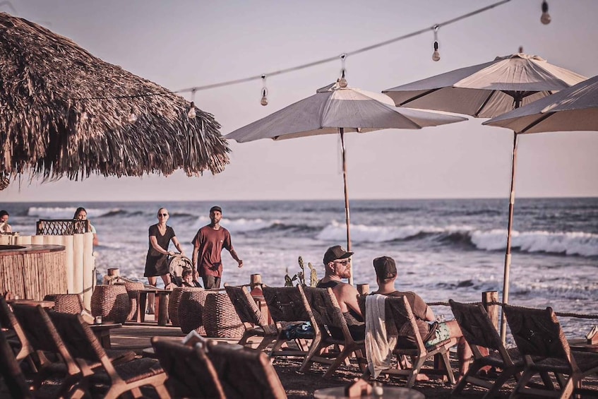 A beachside bar with wicker chairs and umbrellas, overlooking the ocean. 2