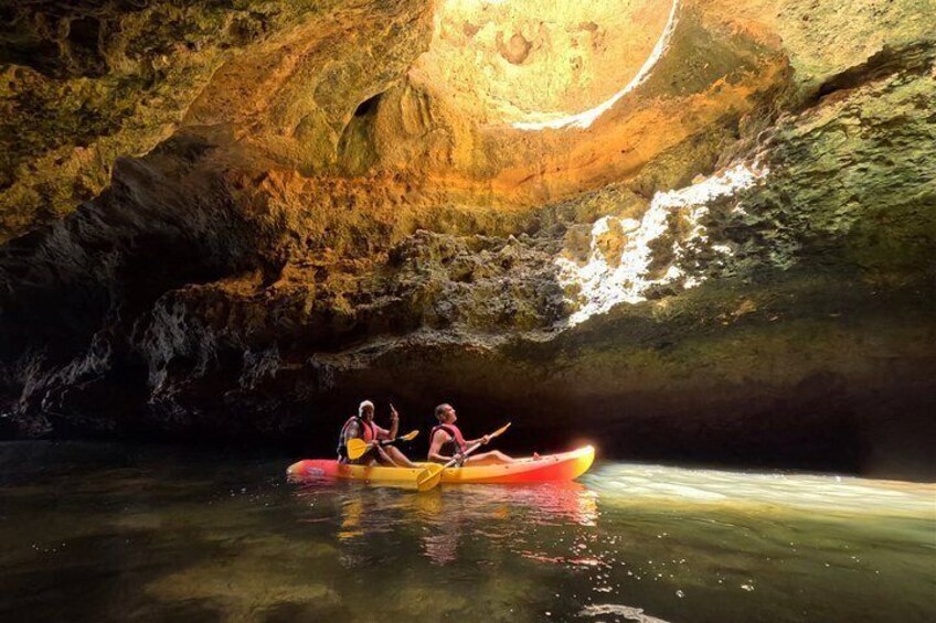 A cave with a water body, a cave opening, and a person kayaking. 4