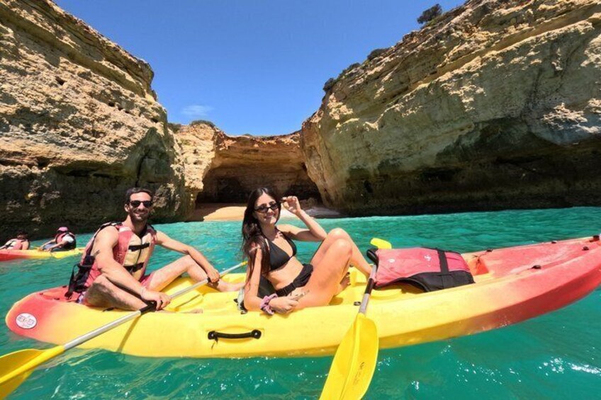 Two people kayaking in a cove with clear turquoise water and rocky cliffs. 5