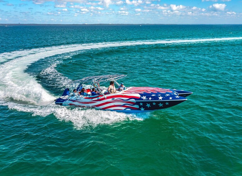 A speedboat with an American flag design on the side, moving through turquoise water. 1