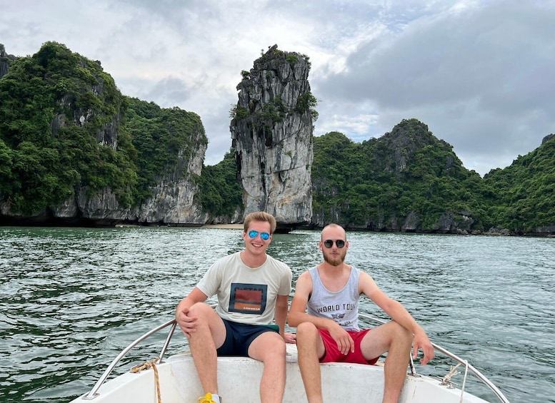 Two people on a boat with a rocky cliff in the background. 4