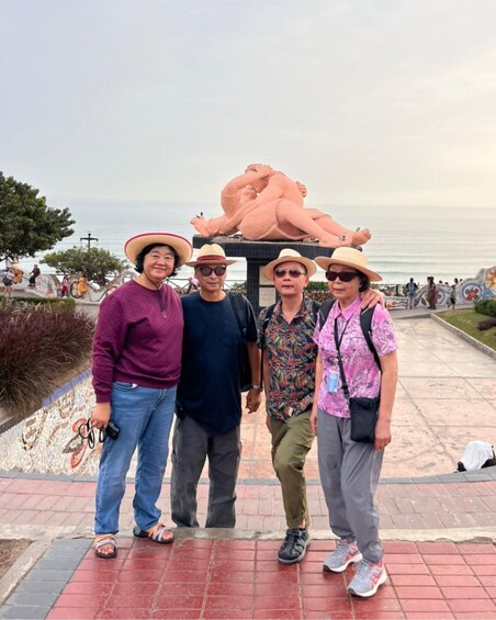 A group of people standing in front of a sculpture with a large hat. 3