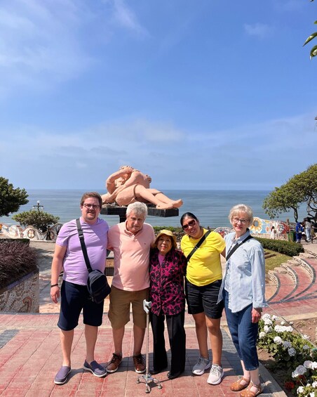 A group of people posing in front of a sculpture by the sea. 5