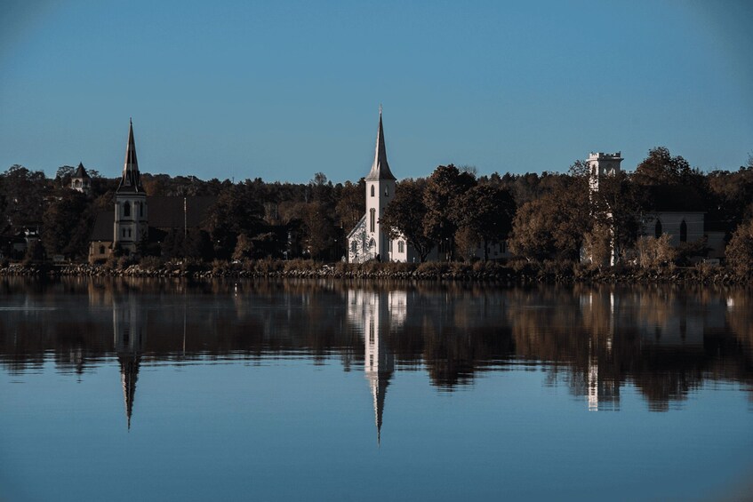A calm lake with reflections of church spires and a tower. 5