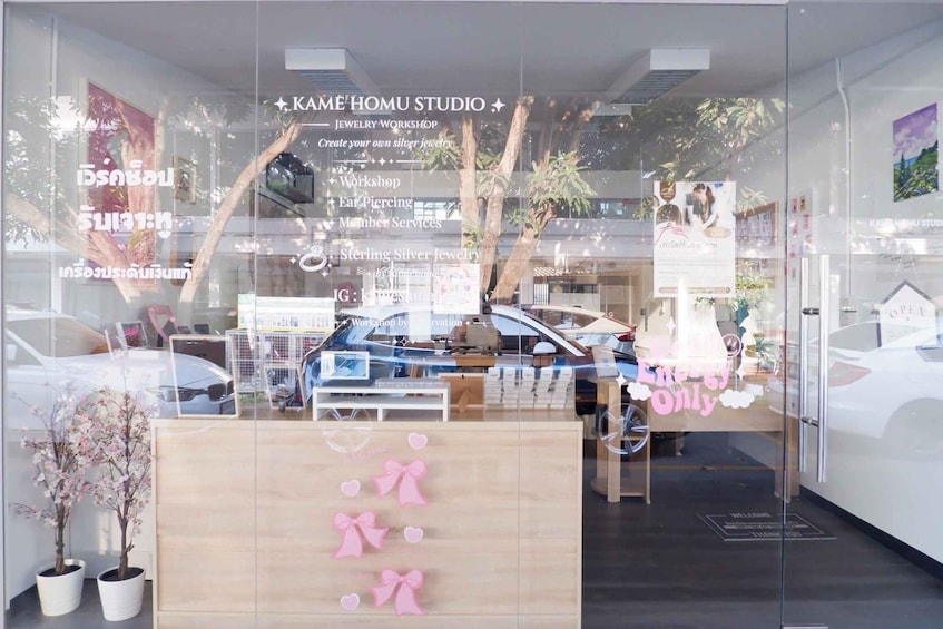 A jewelry workshop with a sign that reads 'KAME HOMU STUDIO' and mentions services like ear piercing and sterling silver jewelry. 5