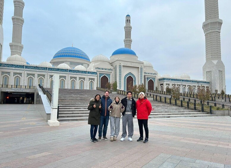 A mosque with blue domes and minarets, a staircase leading to the entrance, and people posing in front. 5