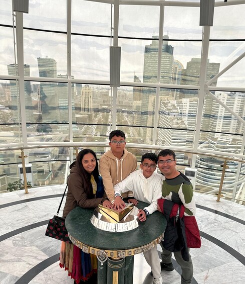 A group of people posing in a high-rise building with a cityscape view. 1