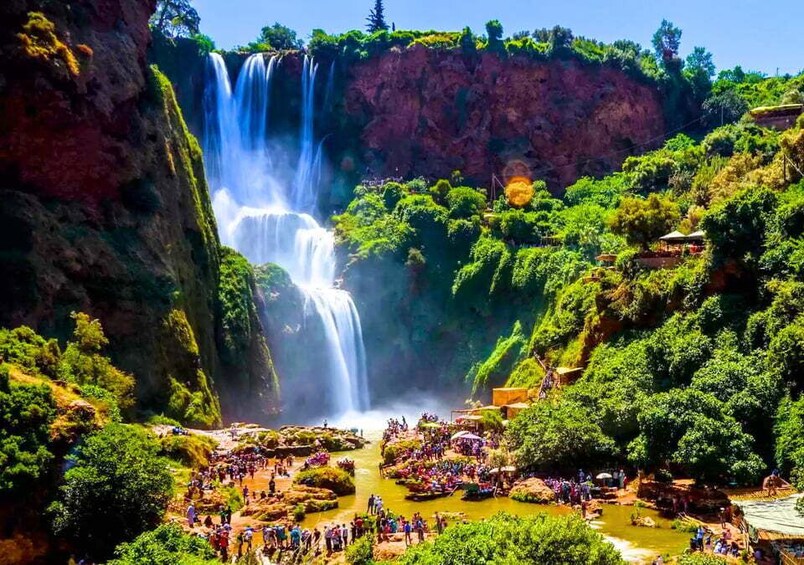 A waterfall surrounded by lush greenery and a crowd of people. 2