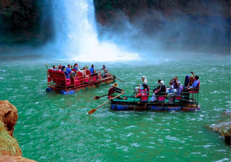 Two boats with passengers on a river with a waterfall in the background. 5