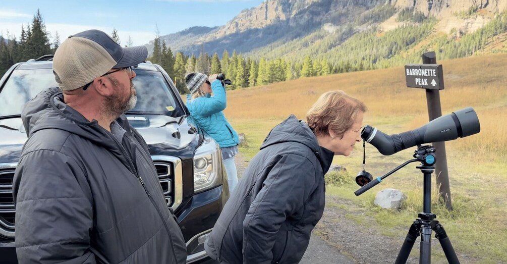 A group of people with a telescope and a sign for Barronette Peak. 5