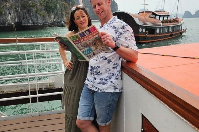 A couple on a boat with a rocky coastline in the background. 3