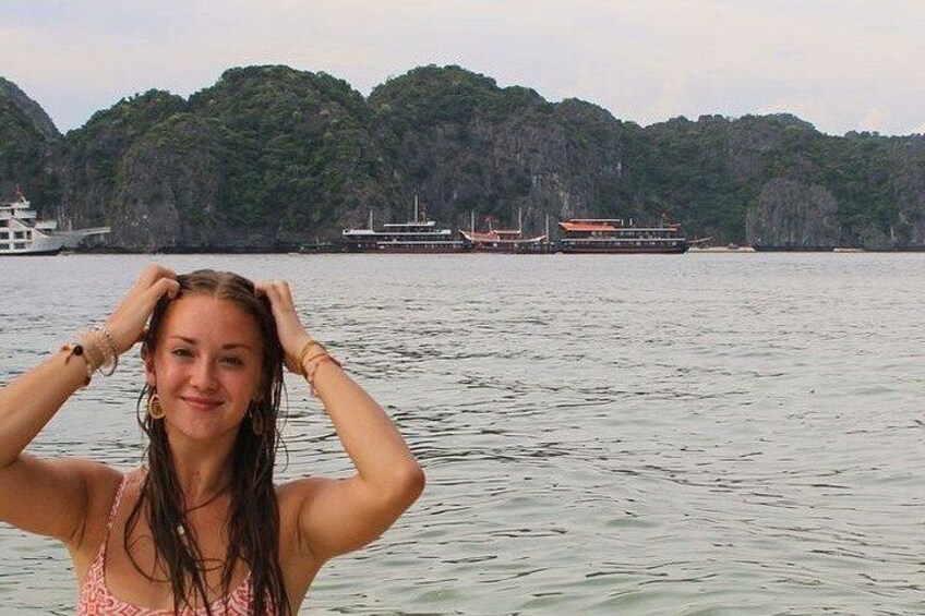 A person standing in water with a boat and hills in the background. 4