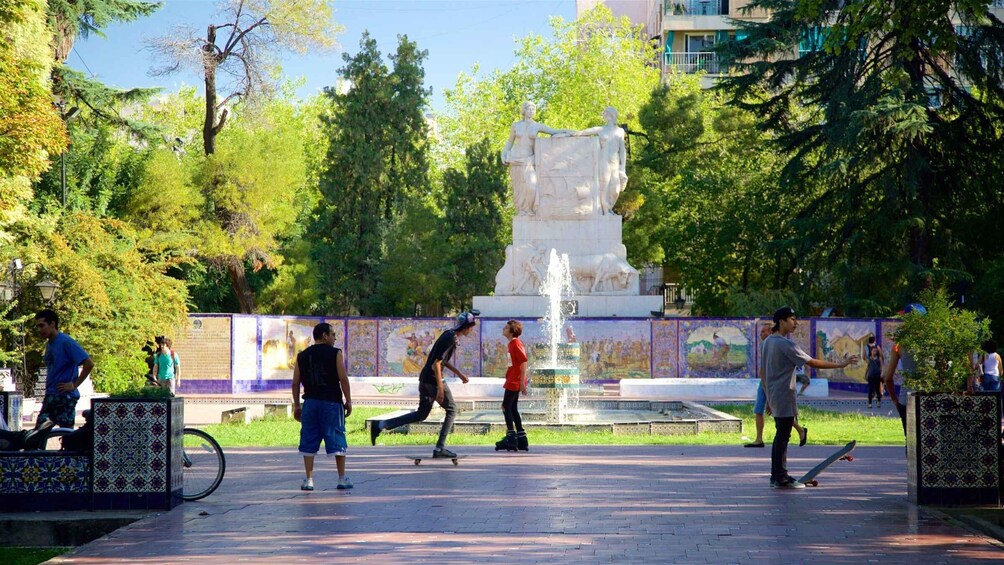 A park with a fountain, skateboarders, and a statue. 5