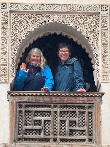 Two people standing in a balcony with intricate architectural carvings. 5
