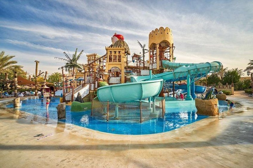Parque acuático con una piscina grande, toboganes y una estructura que parece un castillo. 2